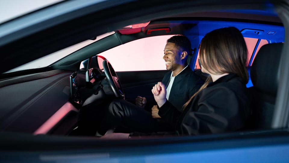 Man sitting in car with passenger laughing